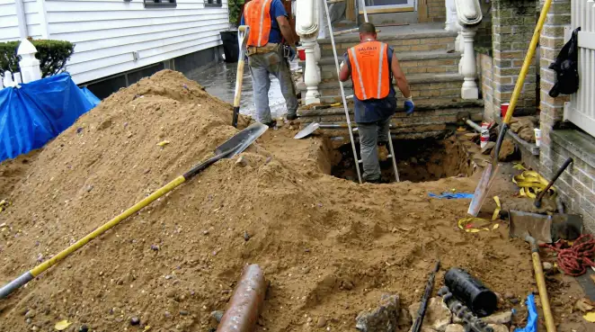 Contractors performing foundation protection and exterior drainage excavation near residential home steps in Gilbert, AZ