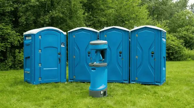 Four blue portable toilets and a matching hand washing station on grass near trees, a common sight at local outdoor events in Gilbert, AZ