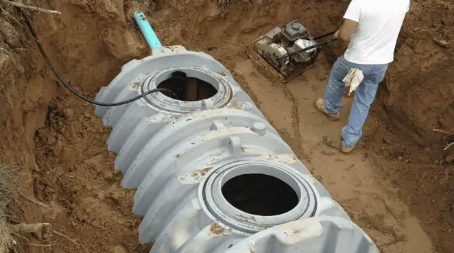 Septic tank installation showing a technician compacting soil around a new poly septic tank in an excavation pit in Gilbert, AZ